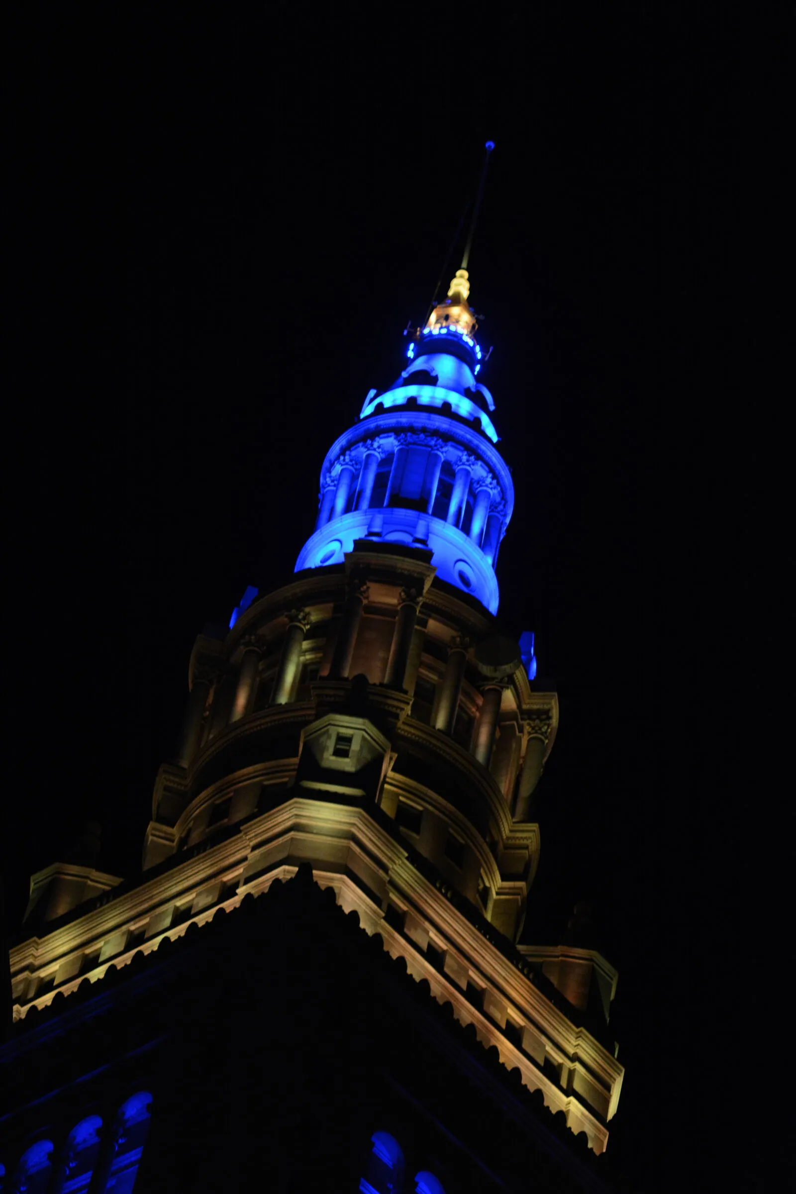 Torre iluminada de azul y amarillo contra el cielo nocturno