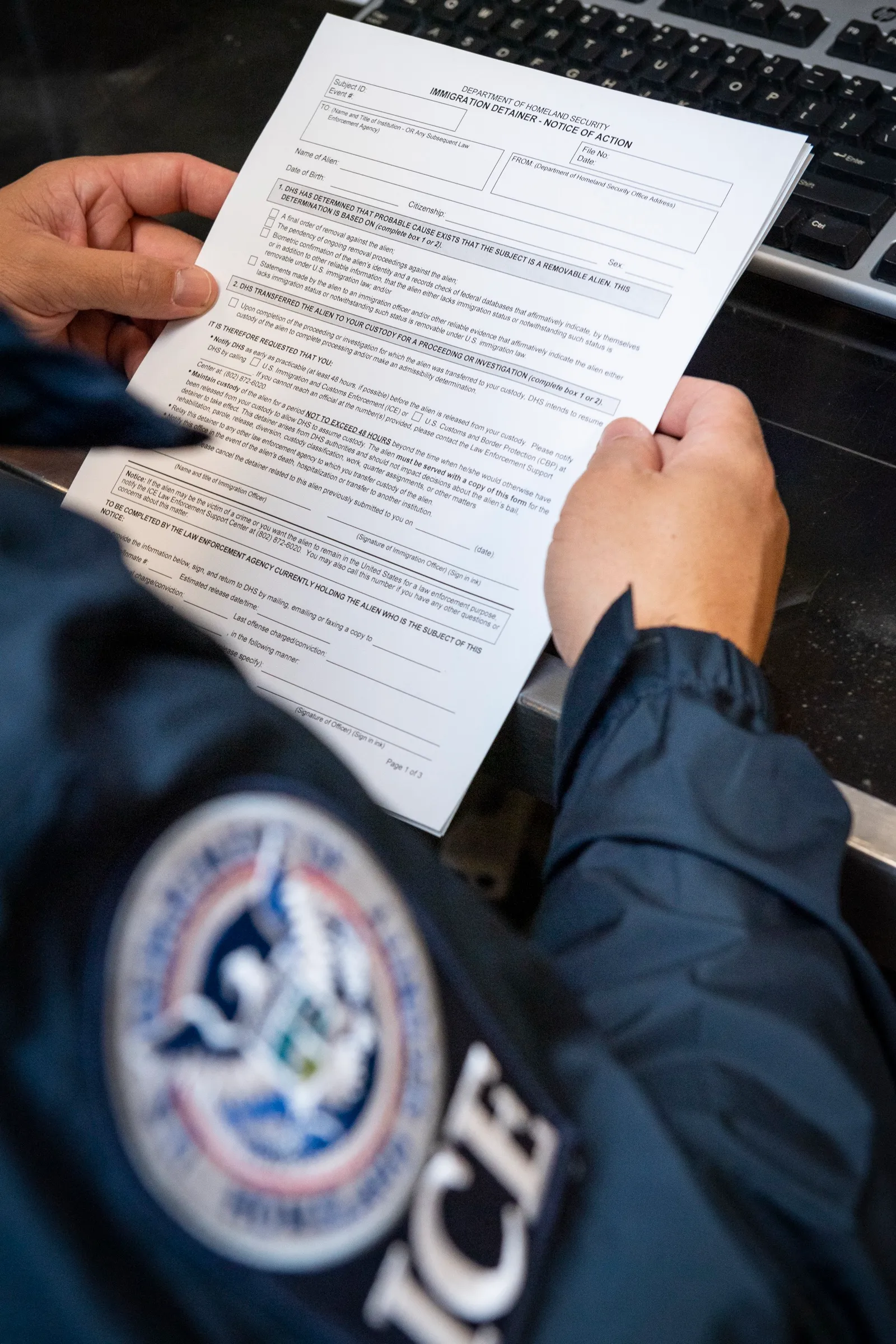 Un oficial del ICE sostiene un formulario de solicitud de detención migratoria (Immigration Detainer)