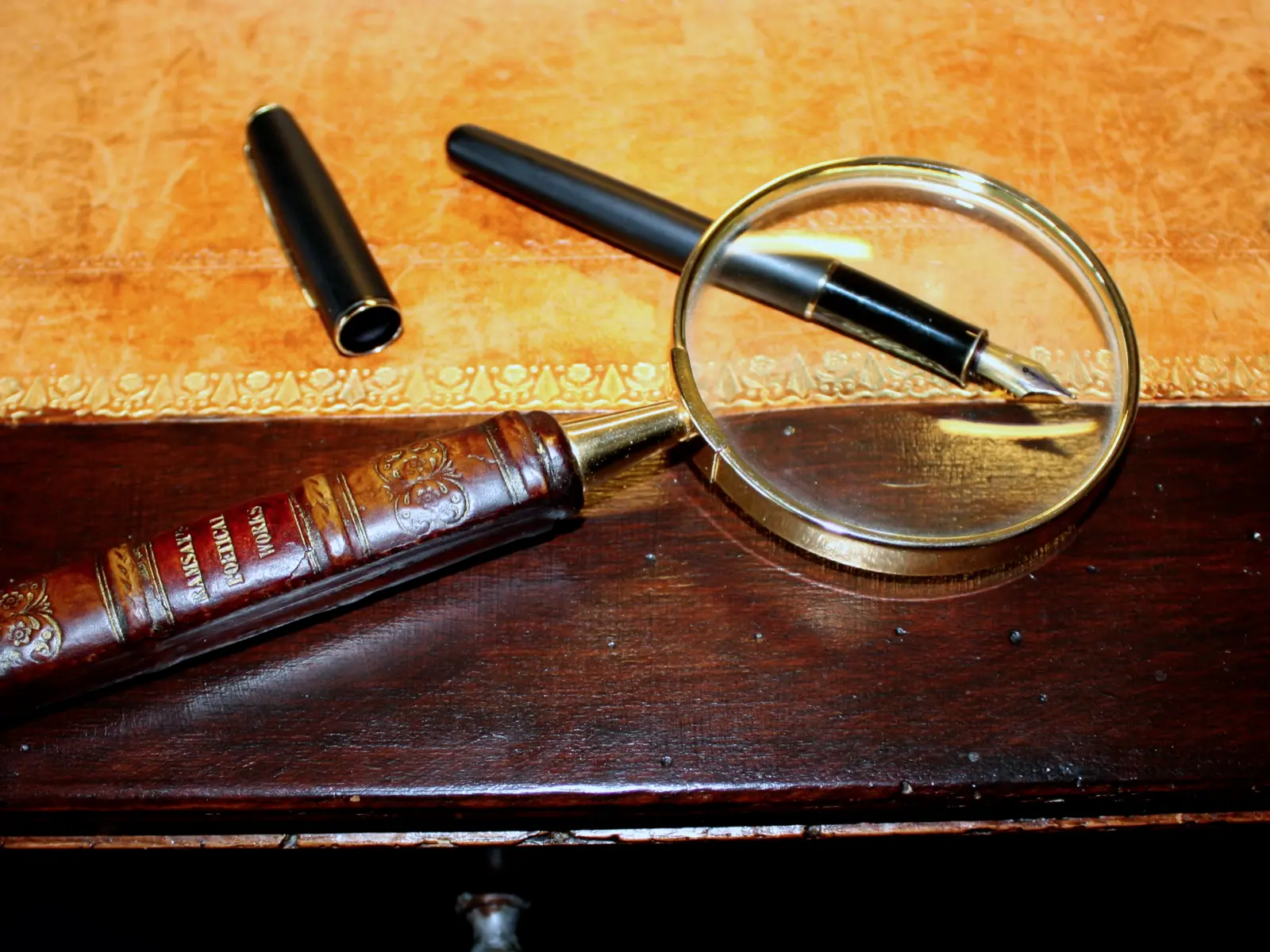 Lupa sobre un escritorio de madera con una pluma fuente