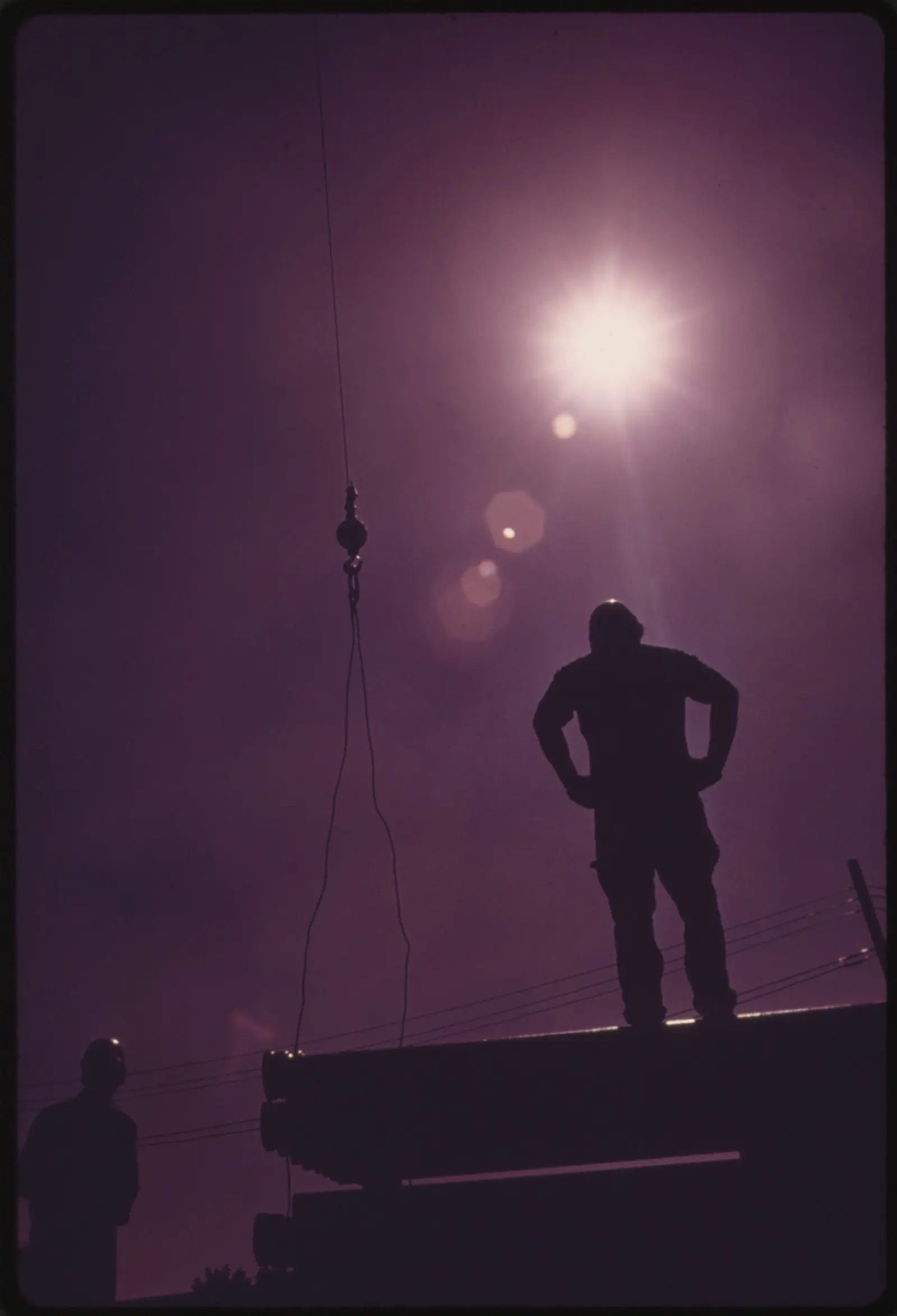 Siluetas de dos obreros contra el sol en una obra de construcción